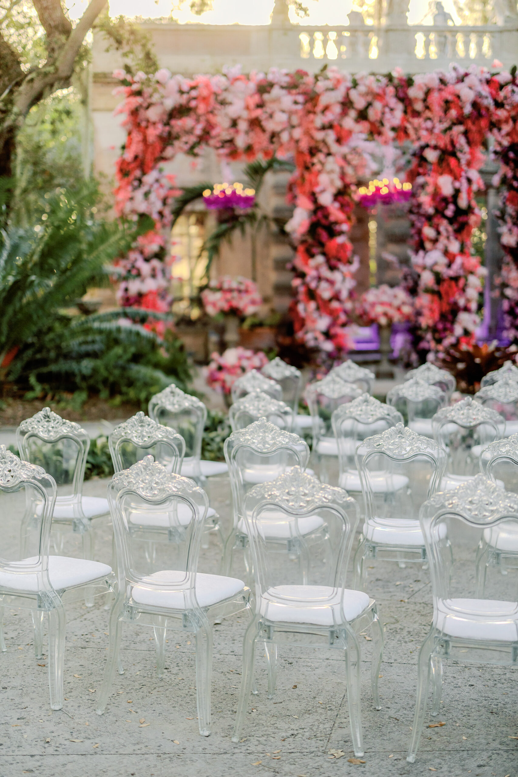 Ghost chairs and ceremony aisle at Vizcaya with floral arch