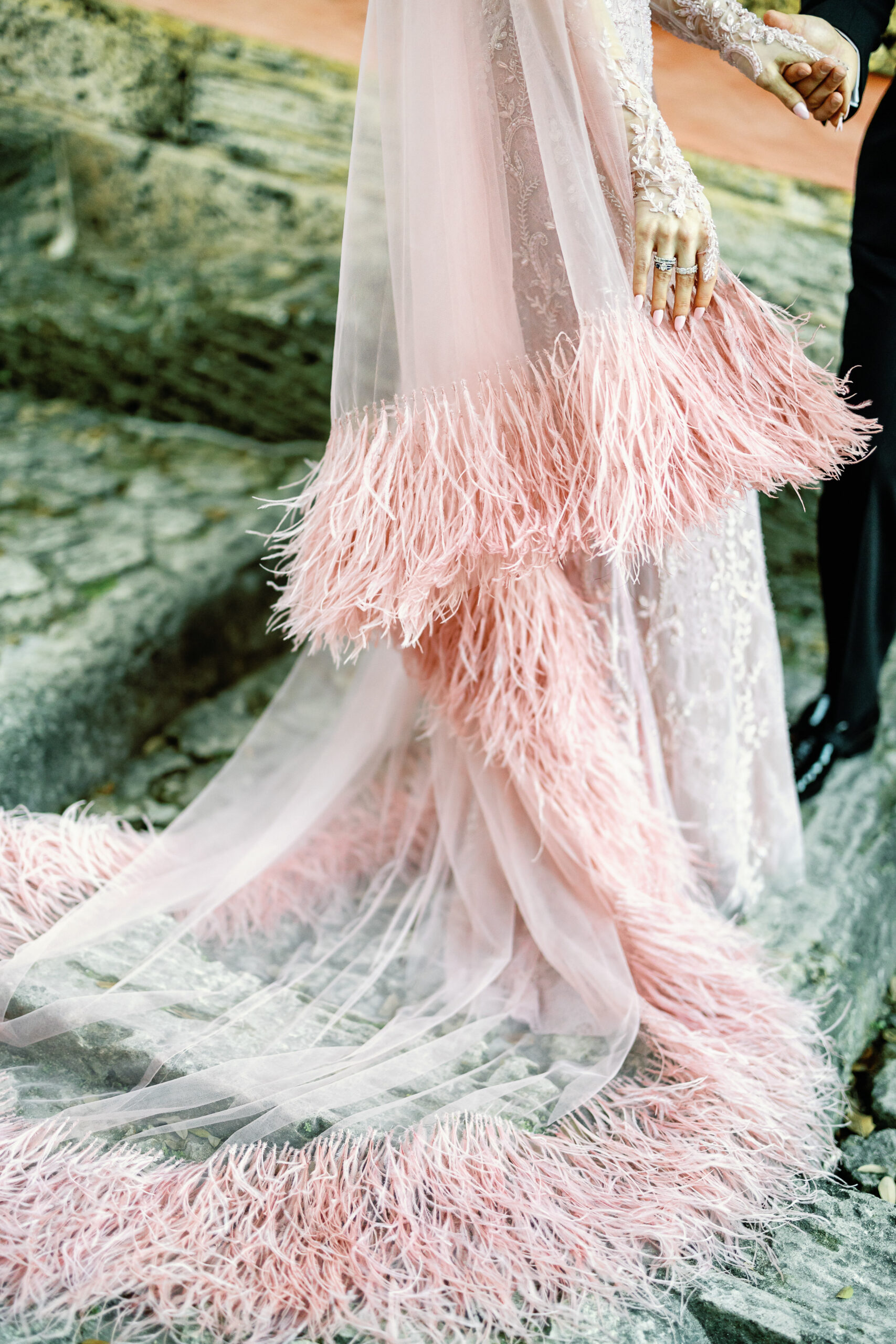 Detail of Bailey's blush feathered gown train and wedding rings
