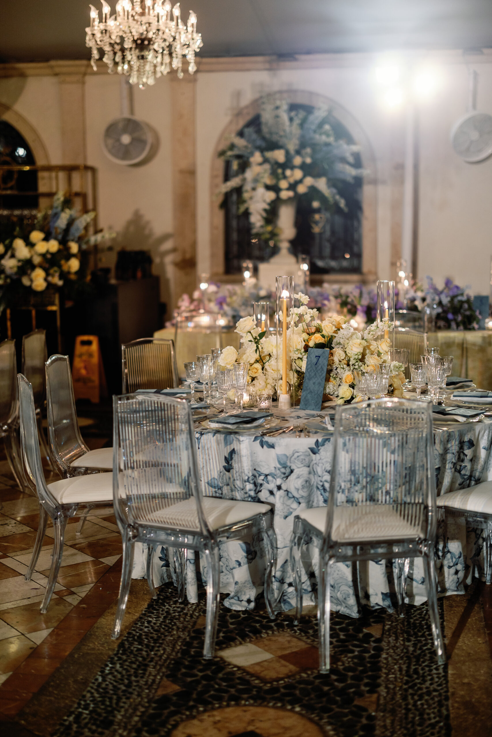 Dinner table with blue floral linen and ghost chairs at Vizcaya reception